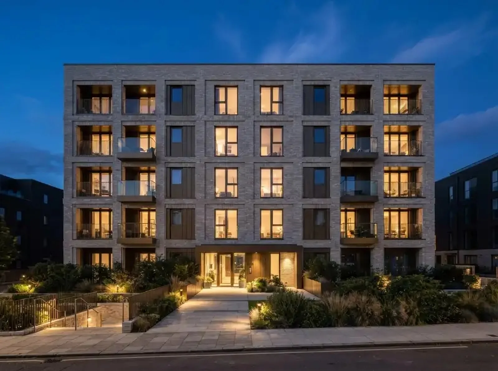A modern brick apartment block lit at dusk